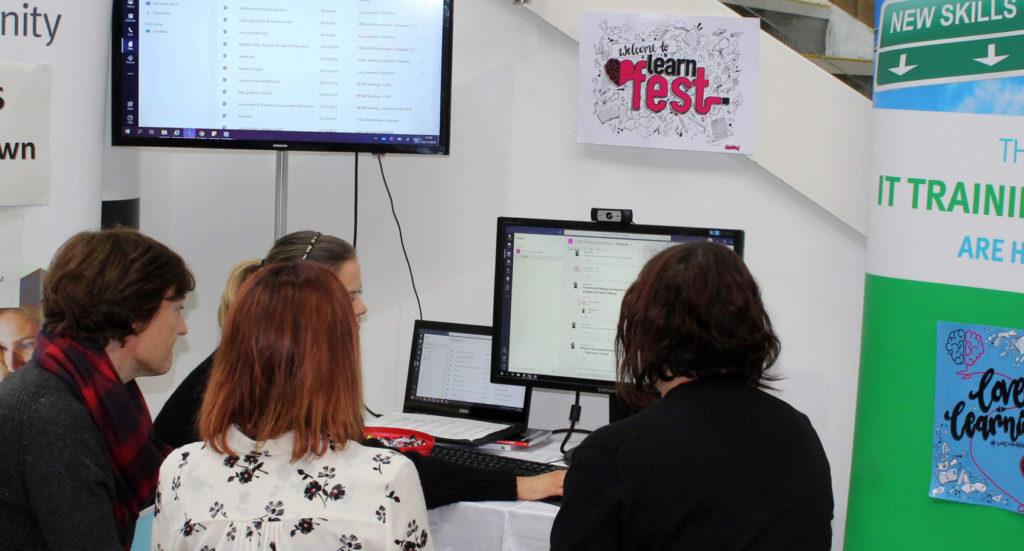 a group of four women working together on a conputer laptop