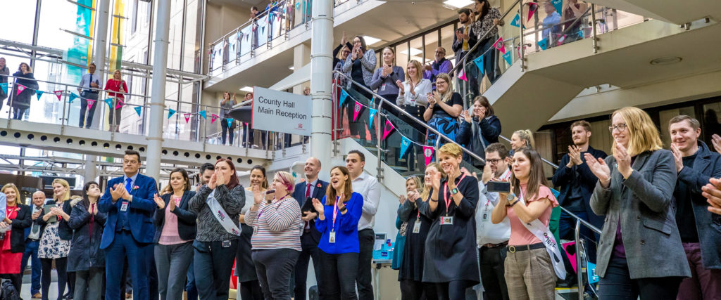 A group of attendees clapping at the end of a presentation.